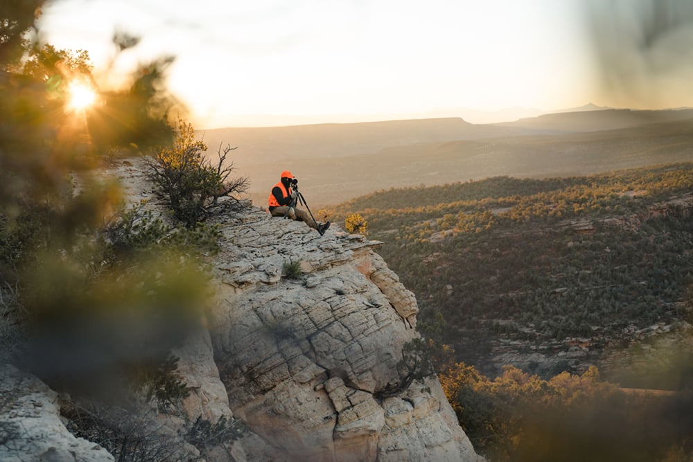 Man sitting on rock face glassing out into the valley floor | SITKA Gear