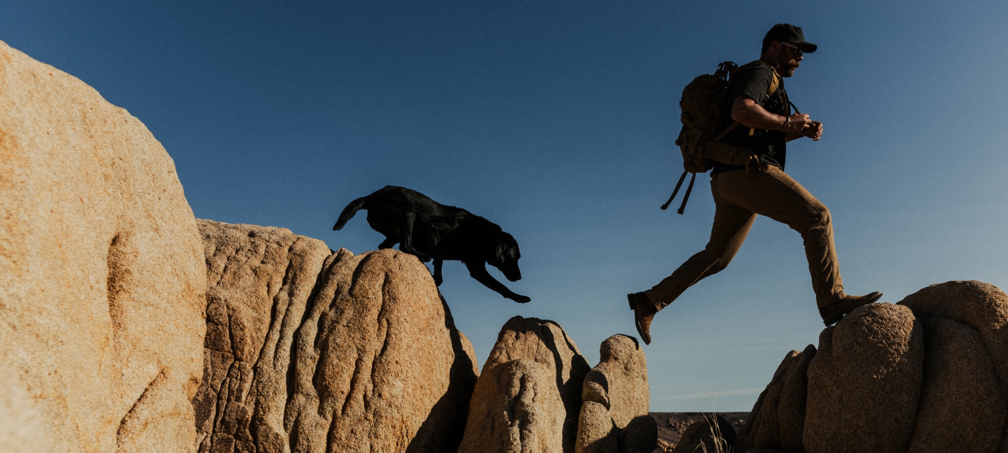 Brad Christian with his dog traversing rocks | SITKA Studio