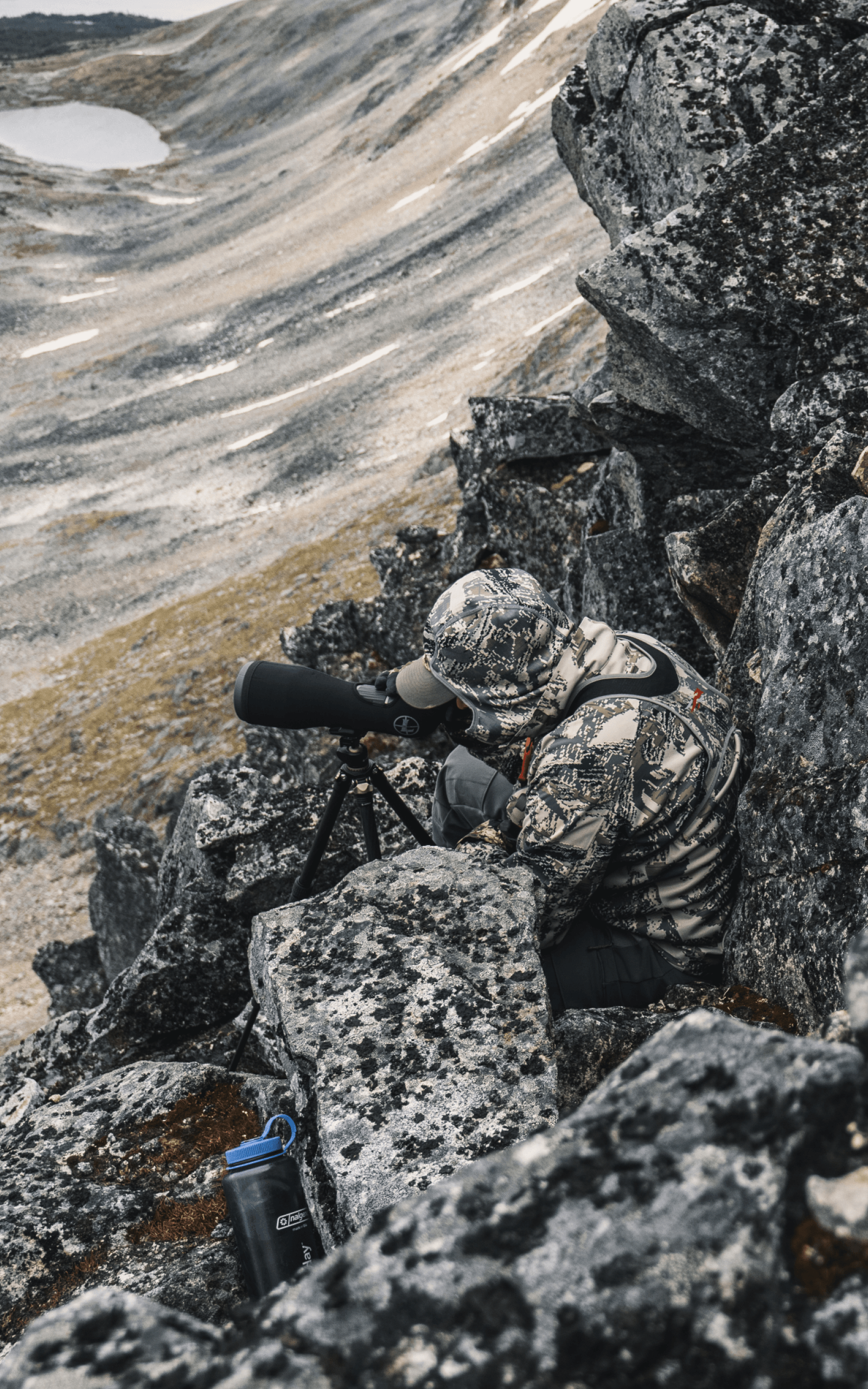 Man blending into rocky face glassing out in Optifade Open Country | SITKA Gear