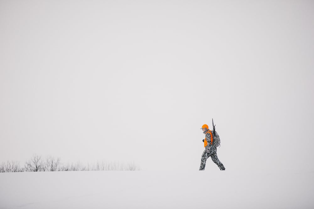 Man walking across a snowy field in the Incinerator Aerolite Collection in Optifade Elevated II | SITKA Gear
