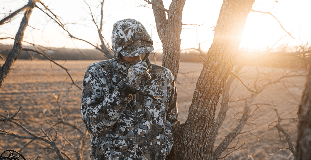 Man in treestand hunkering down in a the wind in the Stratus Collection in Optifade Elevated II | SITKA Gear