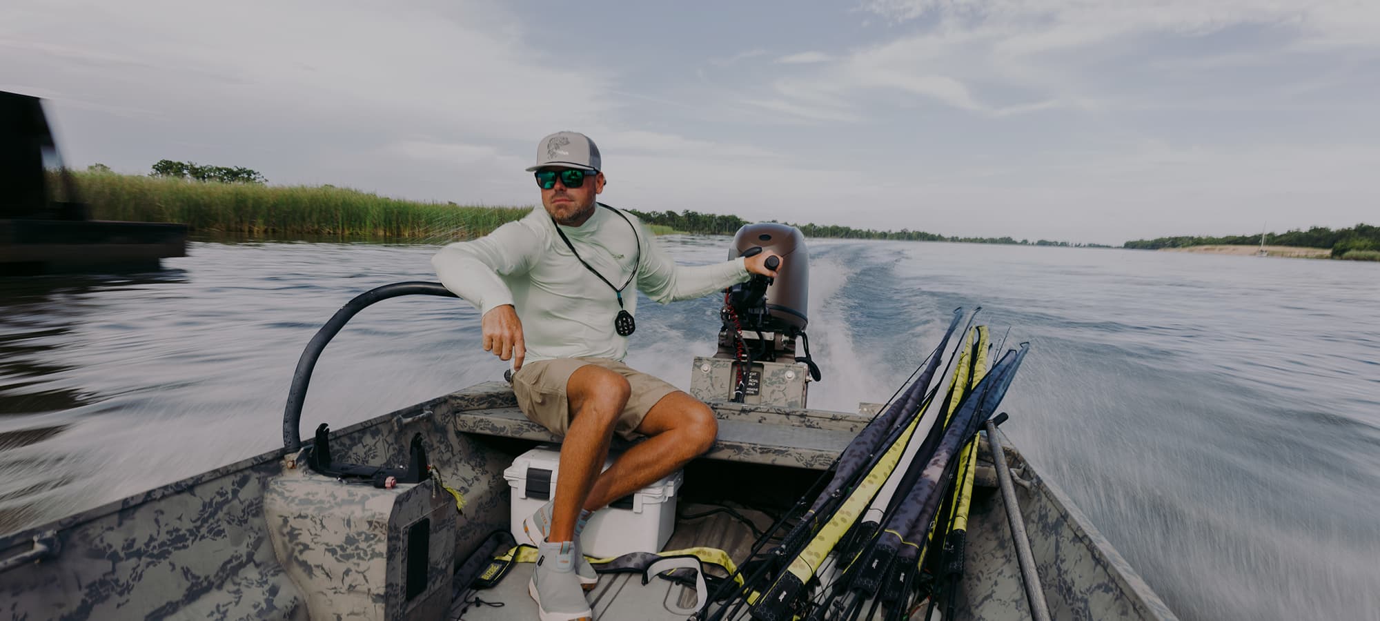 A person driving a boat wearing a sun hoody