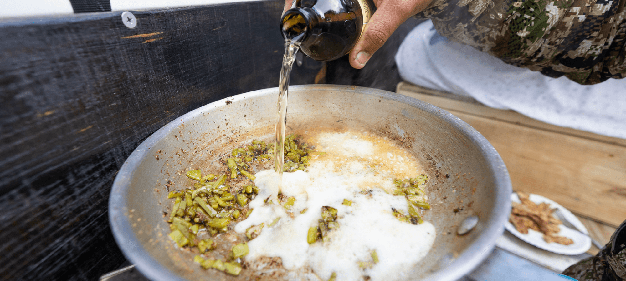 Jonathan Wilkins pouring beer over cut up nopales in a frying pan | SITKA Gear