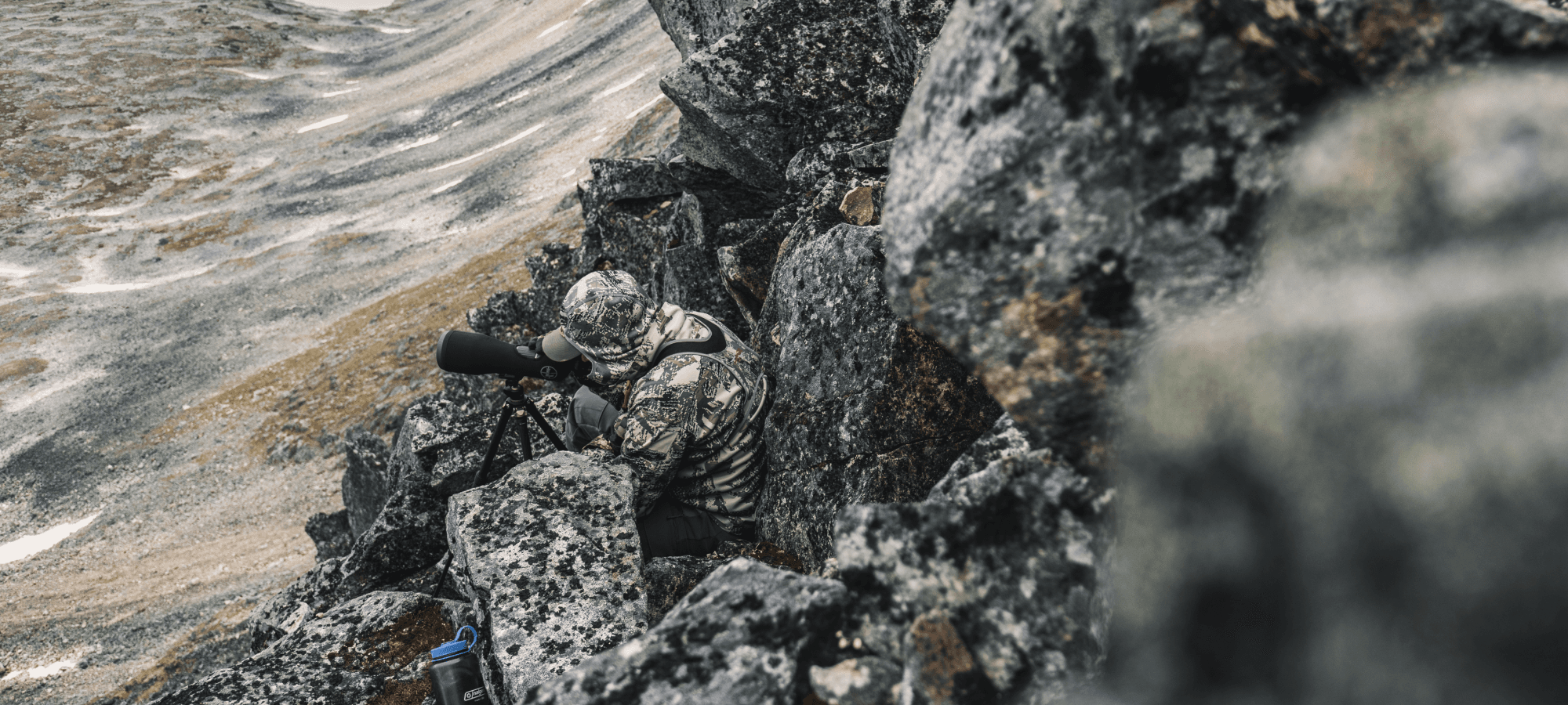 Man blending into rocky face glassing out in Optifade Open Country | SITKA Gear