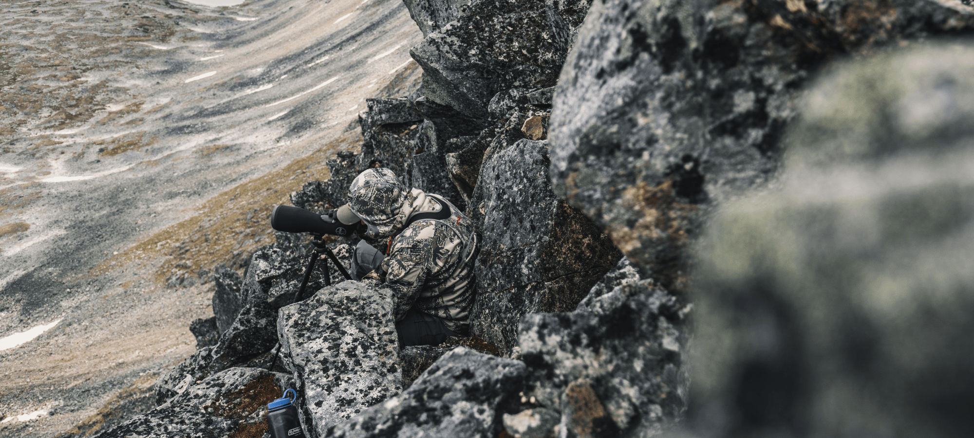 Man blending into rocky face glassing out in Optifade Open Country | SITKA Gear