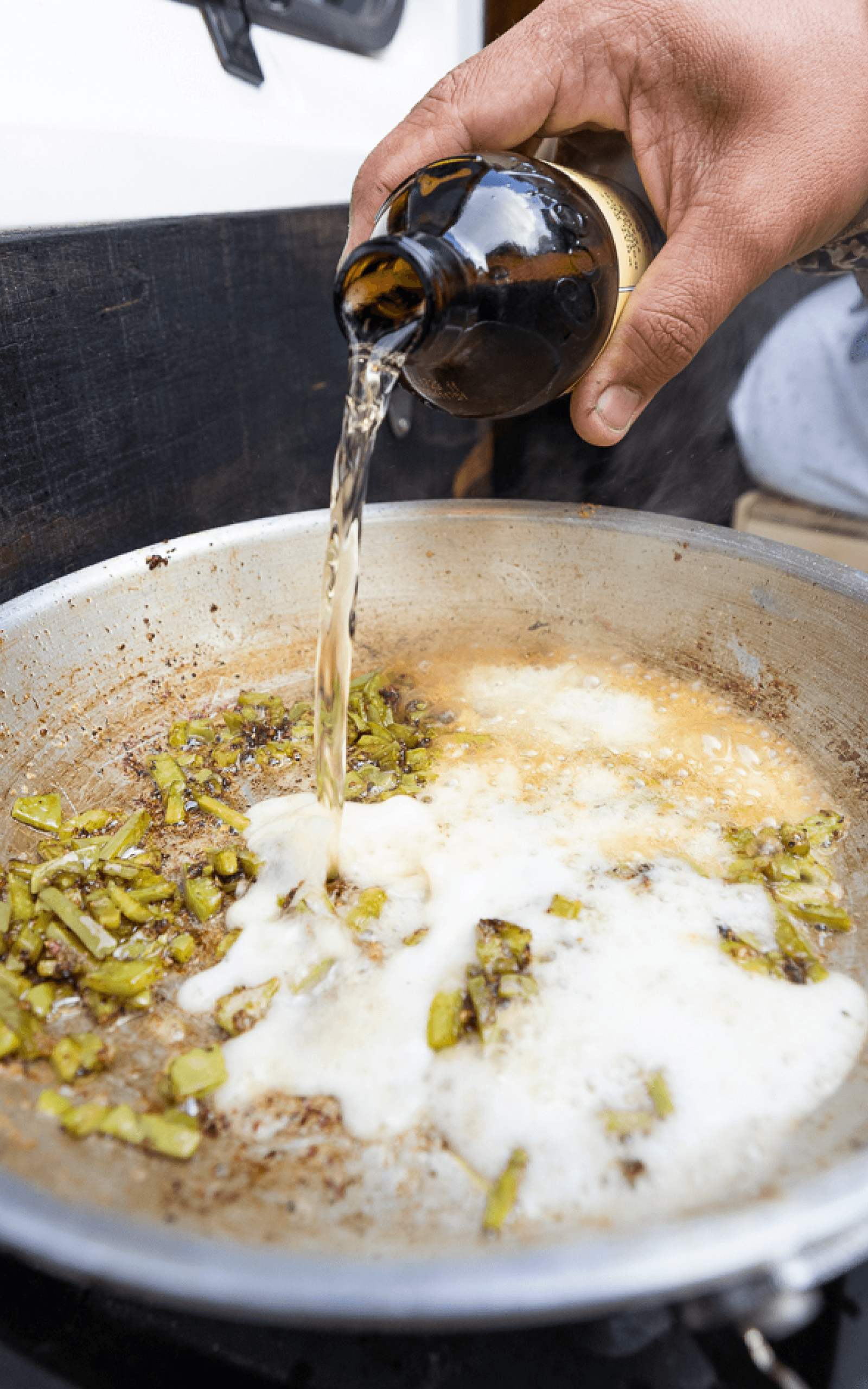 Jonathan Wilkins pouring beer over cut up nopales in a frying pan | SITKA Gear