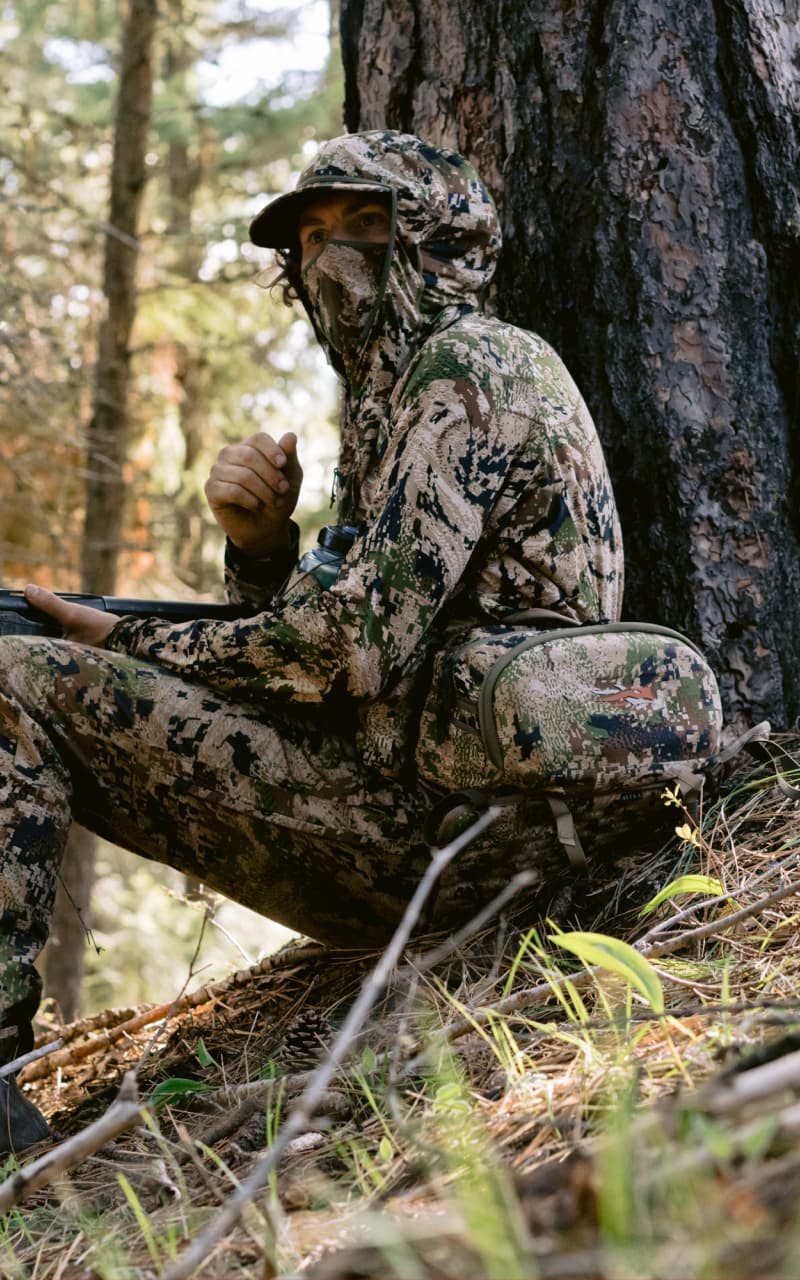 Beau Brooks sitting at the base of a tree wearing the Turkey Tool Belt and Equinox Guard System in Optifade Subalpine | SITKA Gear